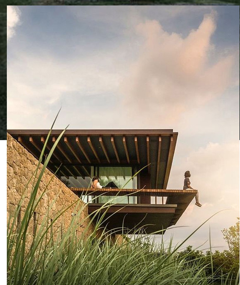 Cantilevered contemporary residence over a stone wall at golden hour